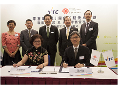 VTC执行干事尤曾家丽（前排左）及香港零售业管理协会副主席叶焯德（前排右），在商务及经济发展局局长苏锦梁（後排中）丶VTC主席陈镇仁博士（後排右二）丶香港零售管理协会执委会成员周允成先生（後排左二）丶VTC零售业训练委员会副主席卫有安（後排右一）及VTC副执行干事陈秀清（後排左一）见证下，代表双方签署合作备忘录，推动零售业「职」学创前路先导计划